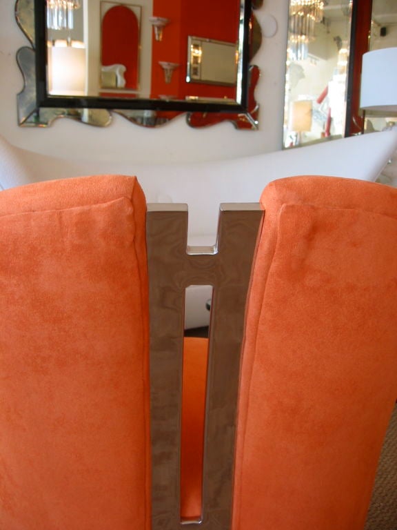 Truly sculptural chairs newly recovered in an orange micro fiber upholstery. Stunning nickel silvered connecting bar running down the center. A show stopper.