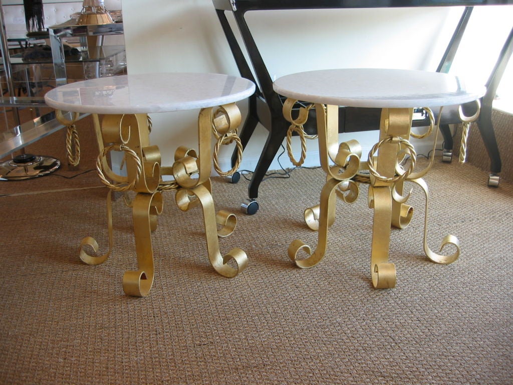 Cette fantastique paire de tables italiennes vintage des années 1960 en fer et feuilles d'or véritable a un léger frottement d'argile rouge et noire sous la feuille d'or. Les bases complexes sont dotées d'anneaux en fer torsadé et de superbes