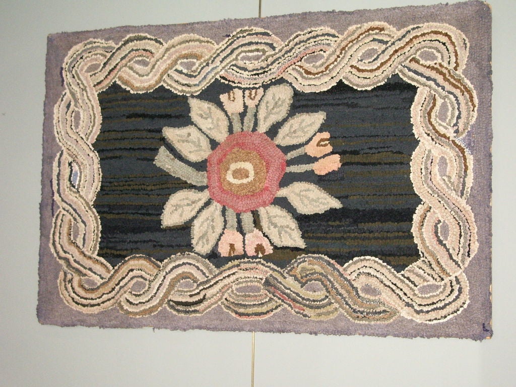 American Hooked Rug with center large floral and rope edge. Rug is on wooden frame for hanging