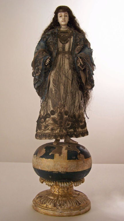 Spanish Colonial saint statue with carved ivory head, hands, feet and human hair. Stands on carved and painted wood orb base. Completely original condition.