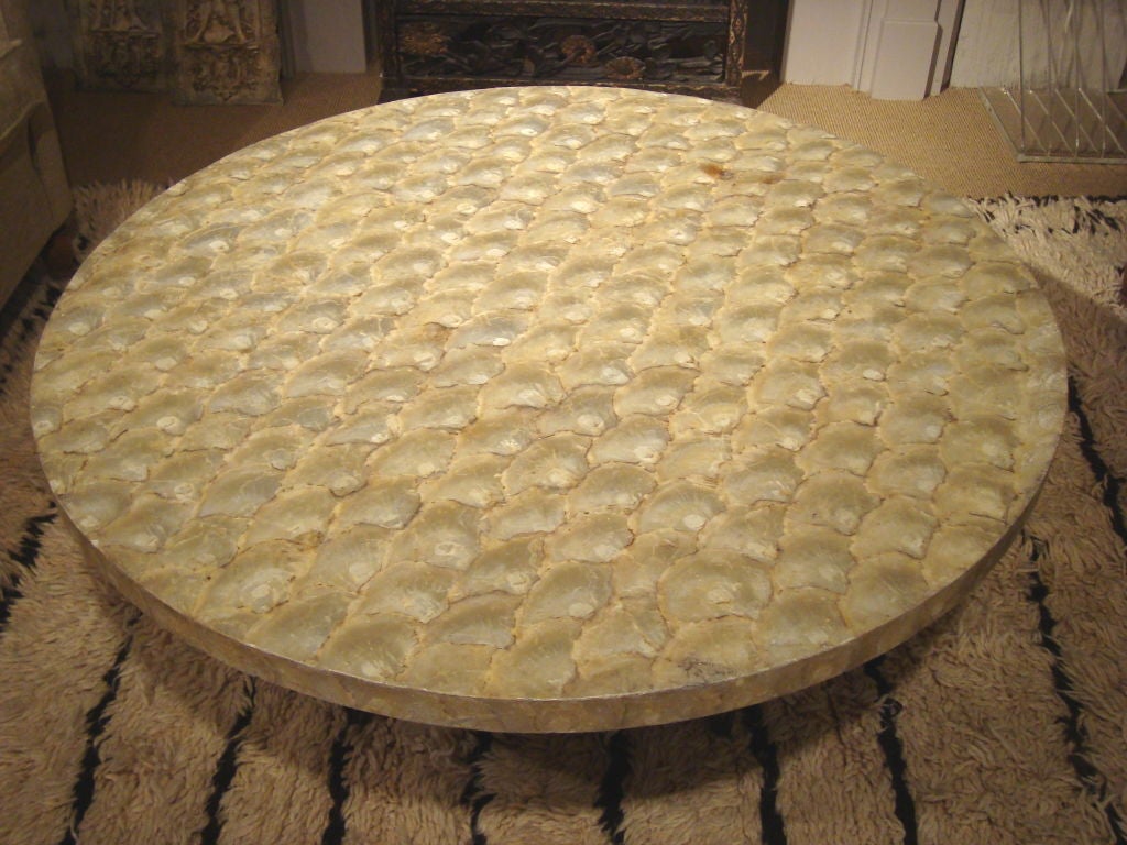 A wonderful capiz shell cocktail table on a hand-made iron base, having a slightly gilt bronze finish.  Capiz shell top has a protective coating of clear urethane over the entire top.