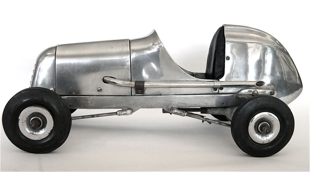 This aluminum racing car was manufactured by Dooling Brothers in the 1930's. It even retains it's original Dooling Brothers tires. It has a great handmade leather seat. The design of this model is the perfect blend of industrial Art Deco and