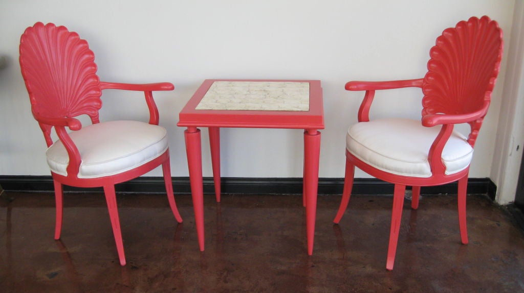 SET OF TWO HAND CARVED SHELL BACK ARM CHAIRS, NEWLY REUPHOLSTERED. WITH A SIDE TABLE LAMINATED WITH REAL SHELLS ON TOP. THE SET HAS BEEN REFINISHED IN GLOSS CORAL PAINT.<br />
CHAIRS H 39