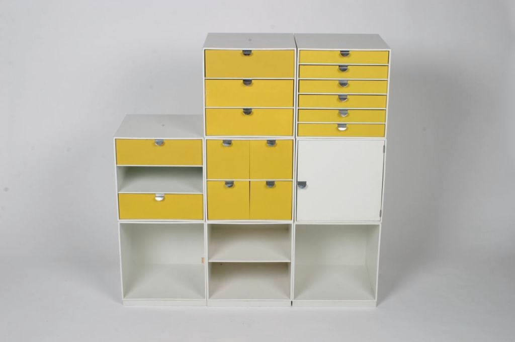 Modular storage cubes, designed to fit together in different configurations, some with yellow front drawers. 3 plastic bases and 8 cubes.