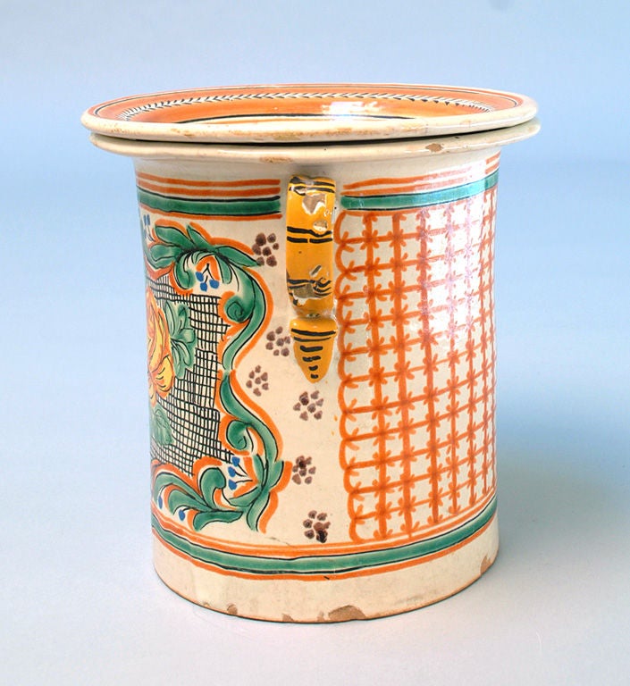 A 19th century double handled Talavera Poblana Vasija with colorful foliate motifs juxtaposed against a red grid of parallel lines - complete with the original lid.