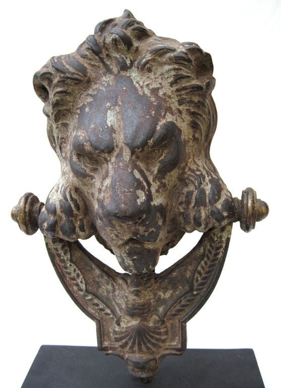 A handsome cast iron lion door knocker with bronze finials