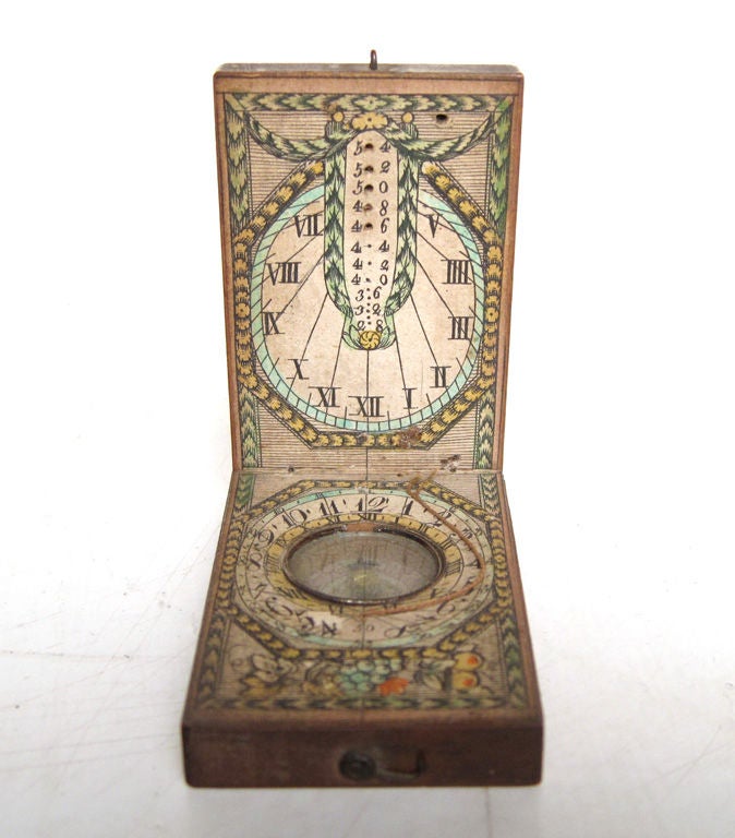 A beautifully-crafted wood pocket sundial with intricate printed paper numerals, degrees and foreign city time zones, with a compass set in its center