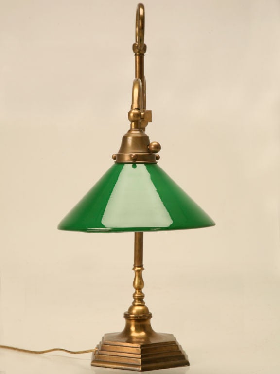 High quality vintage American brass lamp perfect utilized on a desk, end table, or nightstand. Heavy weighted base assures stability, while a swivel head directs light exactly where you need it most. The green cased glass shade gives this beautiful