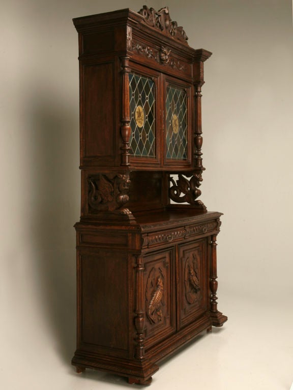 Outstanding antique French cupboard with exquisitely detailed carvings and incredible stained glass doors with gilded bird cameos. Wonderful carvings compliment this entire piece, the lion up top, the birds on the lower doors, and the winged
