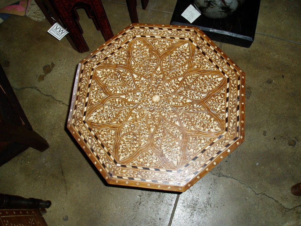 A small octogonal wood table with bone and ebony inlays.  Highly decorative pattern.  Scalloped foldable base also with inlays.