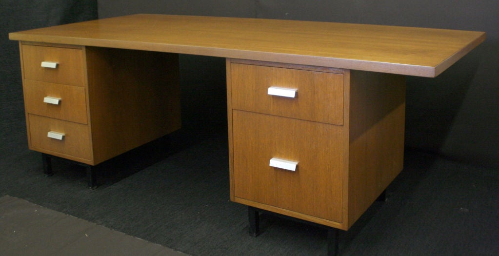 A large executive desk by Alain Richard with two sliding drawer pedestals on black metal legs and five smooth slidingh drawers with extruded aluminum pulls; custom ordered with a top that extends out over the right side of the desk farther than the