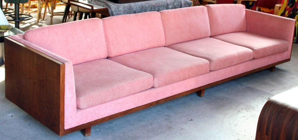 A massive tuxedo arm four seat sofa by Milo Baughman for Thayer Coggin in original light coral color upholstery and framed in dark walnut and set on six legs.