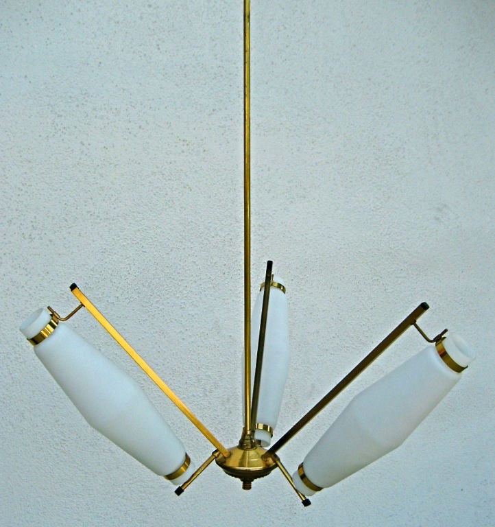 Brass frame holding 3 white glass shades in the style of Stilnovo.  Each arm has a radius of 13