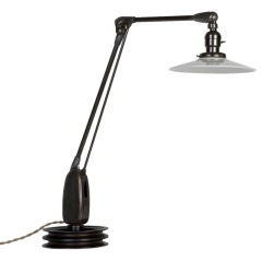 An antique articulating table lamp with a white glass shade