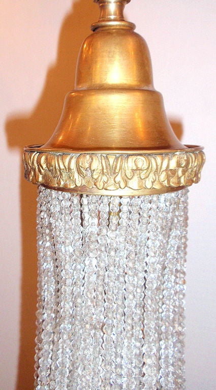 Französischer Bronze-Kronleuchter mit perlenbesetztem Kristallkörper und sechs Armen, um 1920. Vergoldeter Bronzekorpus mit Ranken- und Blattwerkmotiv.