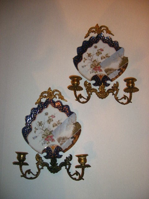 Pair of Japanese porcelain plaques fitted as sconces with gilt metal arms and decorative frieze. Two lights.

Measures: 13