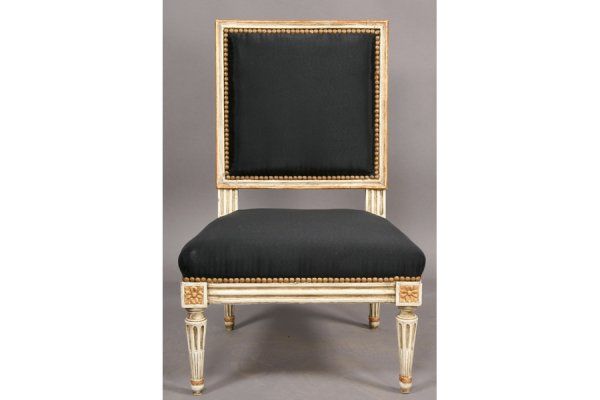 Petite Louis XVI style boudoir chair has a painted and gilt frame,newly upholstered navy back and seat with nail head detail,and fluted, tapered legs.