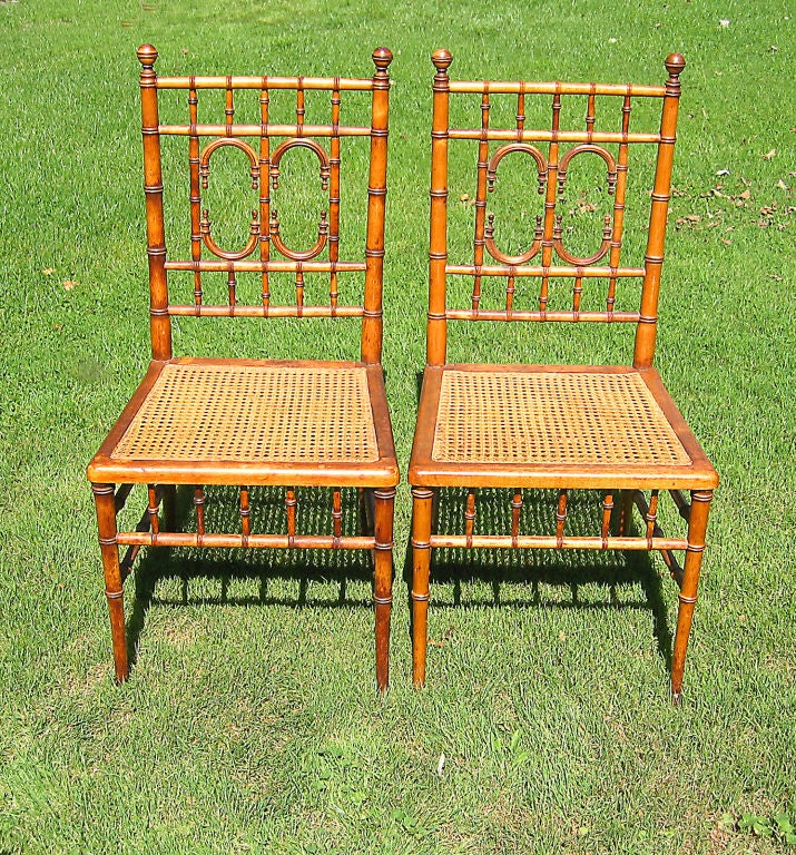 Matching pair of English faux bamboo chairs.  Turned maple frame with aesthetic backrest, ball finials and hand-caned seat of ample proportion.