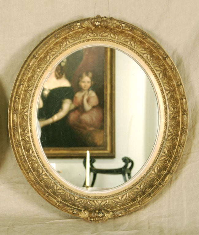 A Pair of Classical American  <br />
Giltwood Mirrors  <br />
19th Century <br />
<br />
Height 25 ½ in. Width 22 ½ in.  <br />
 <br />
      Each with an oval glass mirror surrounded by a detailed carved gilt frame