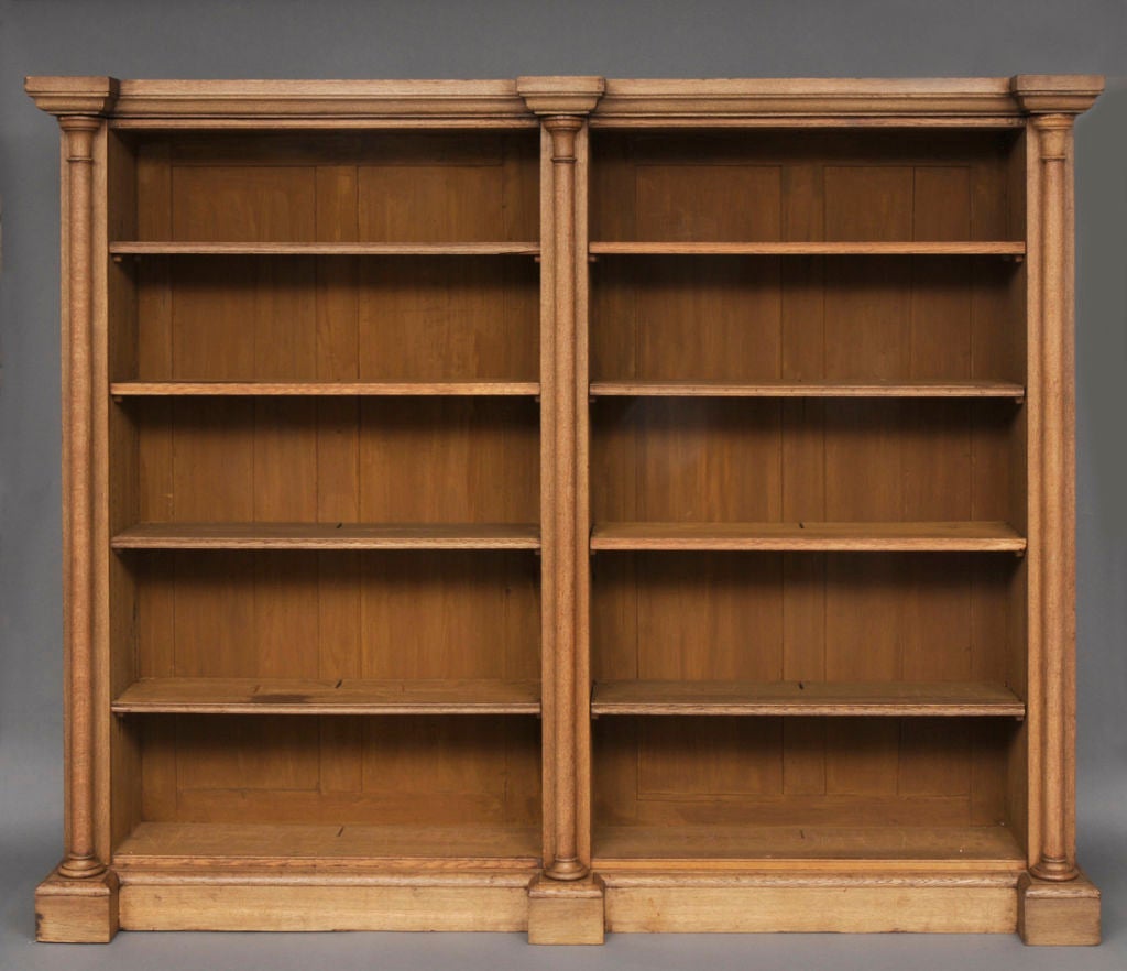William IV bleached oak library open bookcase with breakfront molded cornice, the two sections each with four adjustable shelves, divided by three projecting columns, raised on a plinth base.