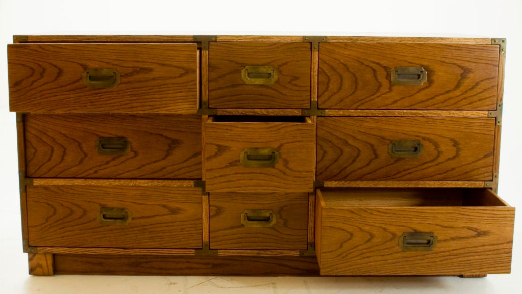 Large-grained oak chest of nine drawers featuring brass pulls and unique studded hardware.