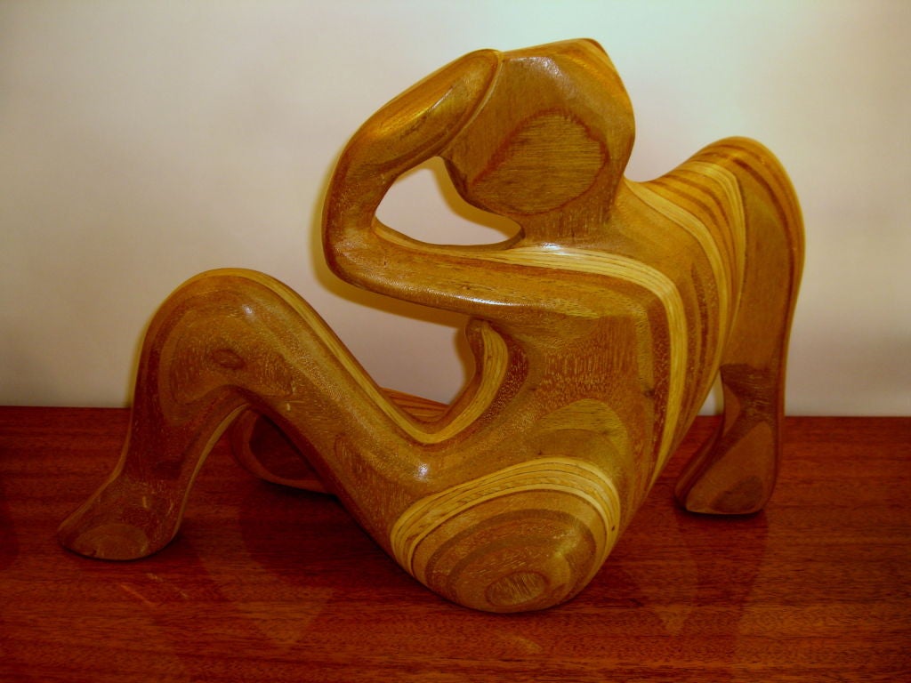 A unique  hand carved sculpture of a woman made of different laminated woods and then carved. As the surface undulates different layers of the wood are exposed rendering the surface a mult colored mosaic. It is signed with a copyright mark R.