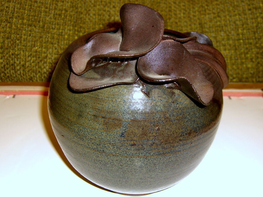 A quite beautiful hand thrown vase with applied floral decoration. It is terracotta and has a nice glaze that alternates from side to side. It is signed but I cannot read the name.