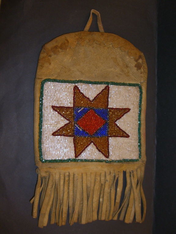 A nice old early Native American Indian beaded bag made of deerskin. It's handle it pinned to the interior. It is beaded on both sides and features elegant designs.