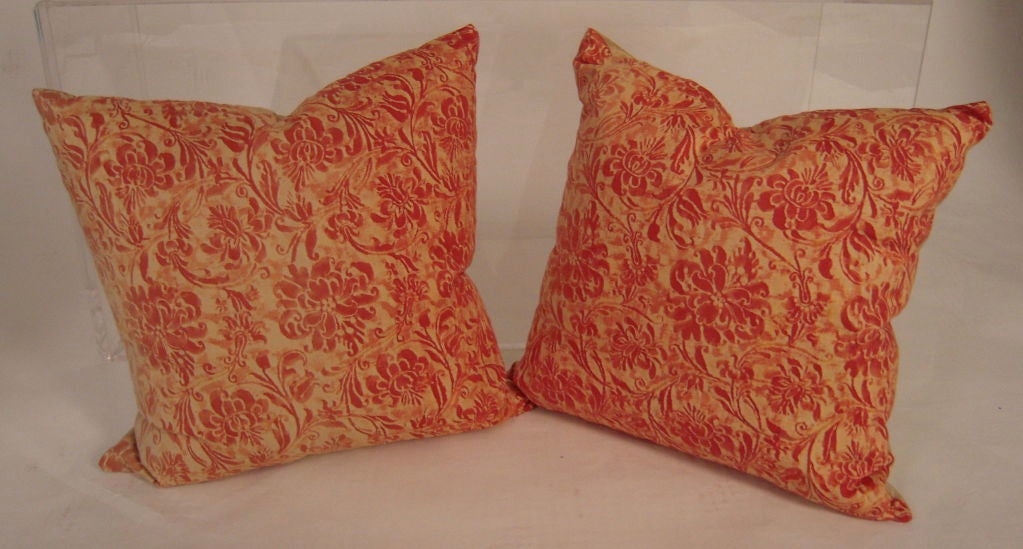 Two pillows made with vintage Fortuny fabric, with floral design  in tomato red and cream, down filled and backed with silk.