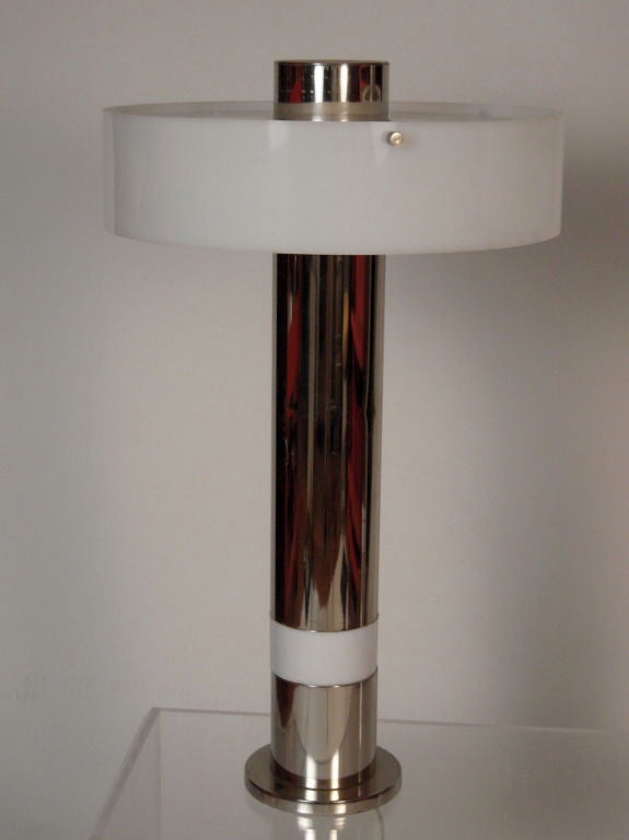 Pair of chrome column lamps with white plastic shades with metal diffusers and white ring at base of each. Lamps may be illuminated in various settings at top and also at bottom where ring is, for ambient light.