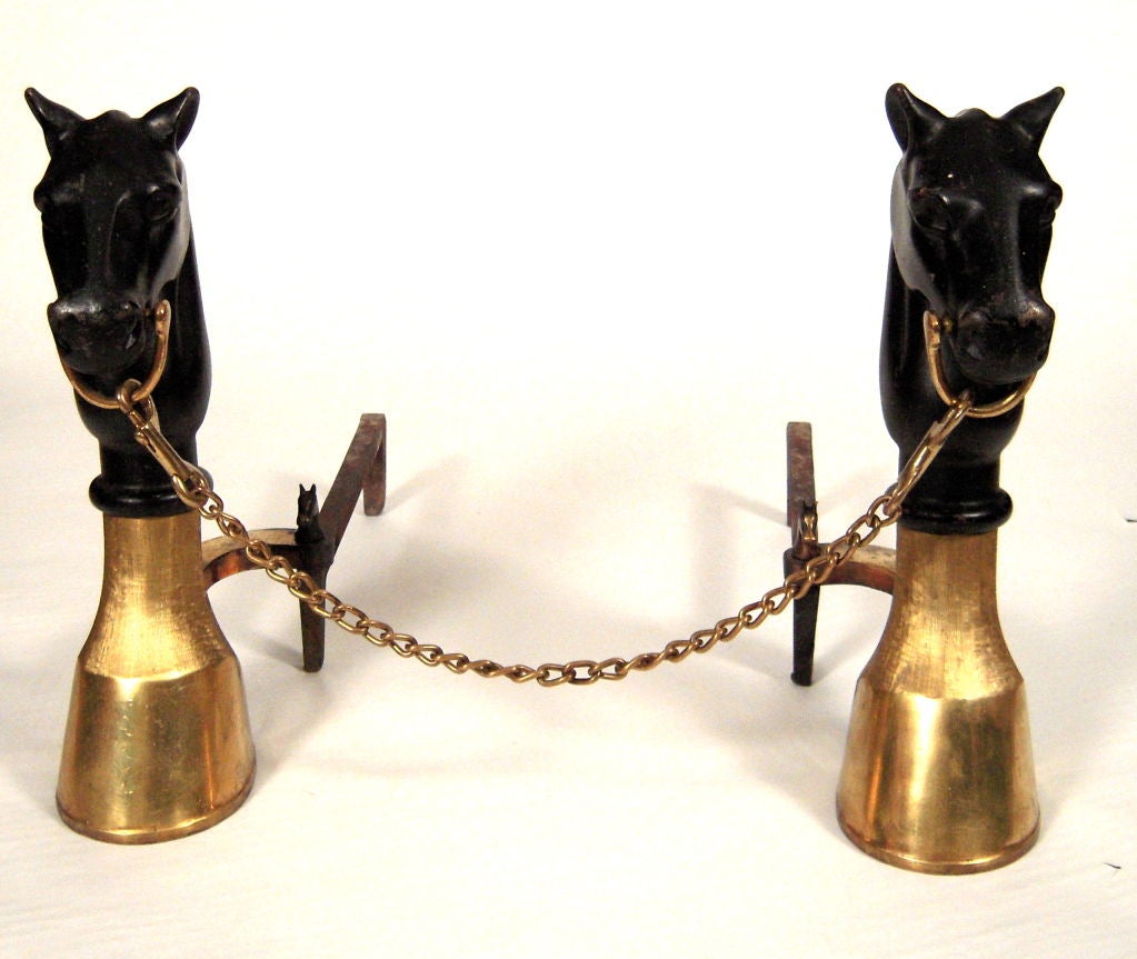 A stylish pair of good quality black painted cast iron and polished brass andirons, the 2 horse head and feet andirons linked by a removable brass chain, together with a complete set of matching fire tools, all decorated with horse head and horse