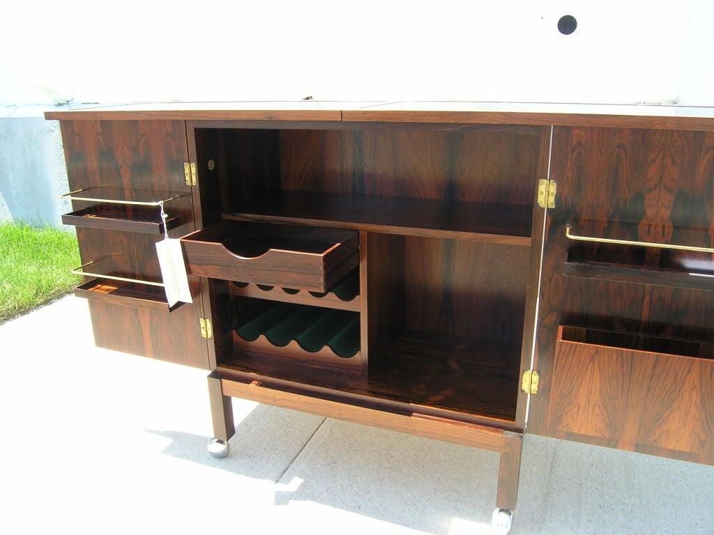 This rosewood bar is beautifully crafted and in like-new condition. The grain of the rosewood is superb from all sides. The top slides and folds open to reveal double the surface space and the doors can be locked open to support the extended top.