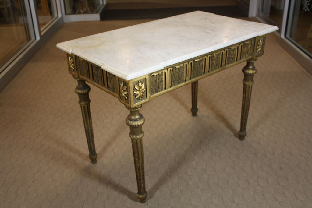 Italian period console table, parcel gilt and polychrome with white marble top. The apron is pierced on three sides and features beautifully carved acanthus leaves. The corner joints have large rosettes, and the legs are fluted with carved asparagus