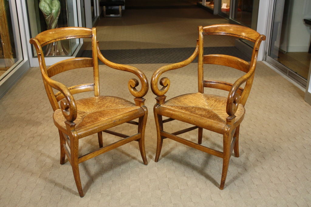 Pair of French scroll armchairs with rush seats, saber legs, slat backs. It appears the backs were originally upholstered. The chairs are quite comfortable and sturdy, but wobble a bit.