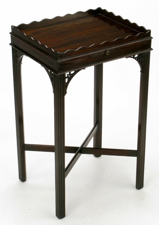 A classic and petite Chippendale mahogany end table from the legendary Chicago furniture maker, Quigley. The top gallery is scalloped and there is a tooled leather pull out writing or drink tray. Well excecuted and detailed corner corbels and center