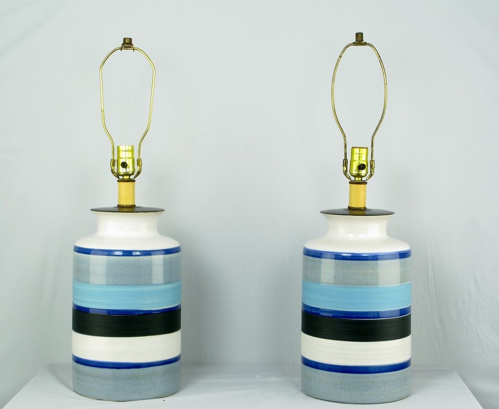 These wonderful and substantial table lamps have hand thrown pottery bodies, vibrant blue and black glazed horizontal stripes on a white ground. Sold sans shades