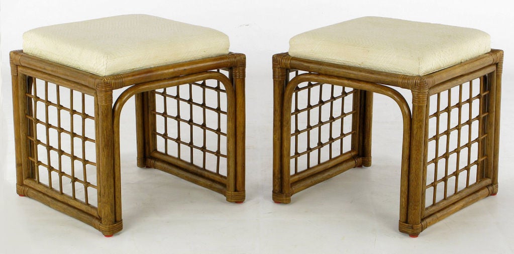 These rattan benches/stools feature cane wrapped corners and bases, as well as cane wrapped cross hatch side panels. The patterned Haitian cotton upholstery is original, and in lovely condition.