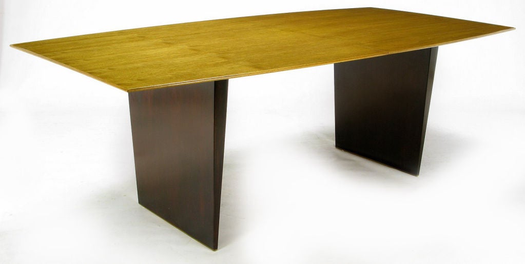 An iconic piece, rarely available, this is one of Wormley's most extraordinary dining table designs. Figured tawi wood top, two tapered mahogany wood legs, and brass shoes. This would also make an exquisite executive desk. Comes with three 12