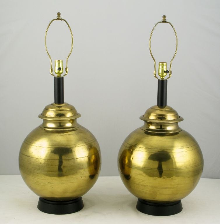 An exquisite pair of very large spun and hammered brass table lamps, with black lacquered wood bases and metal stem. These are a custom designed pair of the highest quality; the  home from which we acquired these was also filled with pieces designed