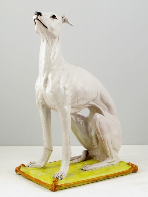 Excellent life size ceramic statue of a white whippet on a yellow and tangerine orange glazed ceramic bed. Marked Italy and numbered.