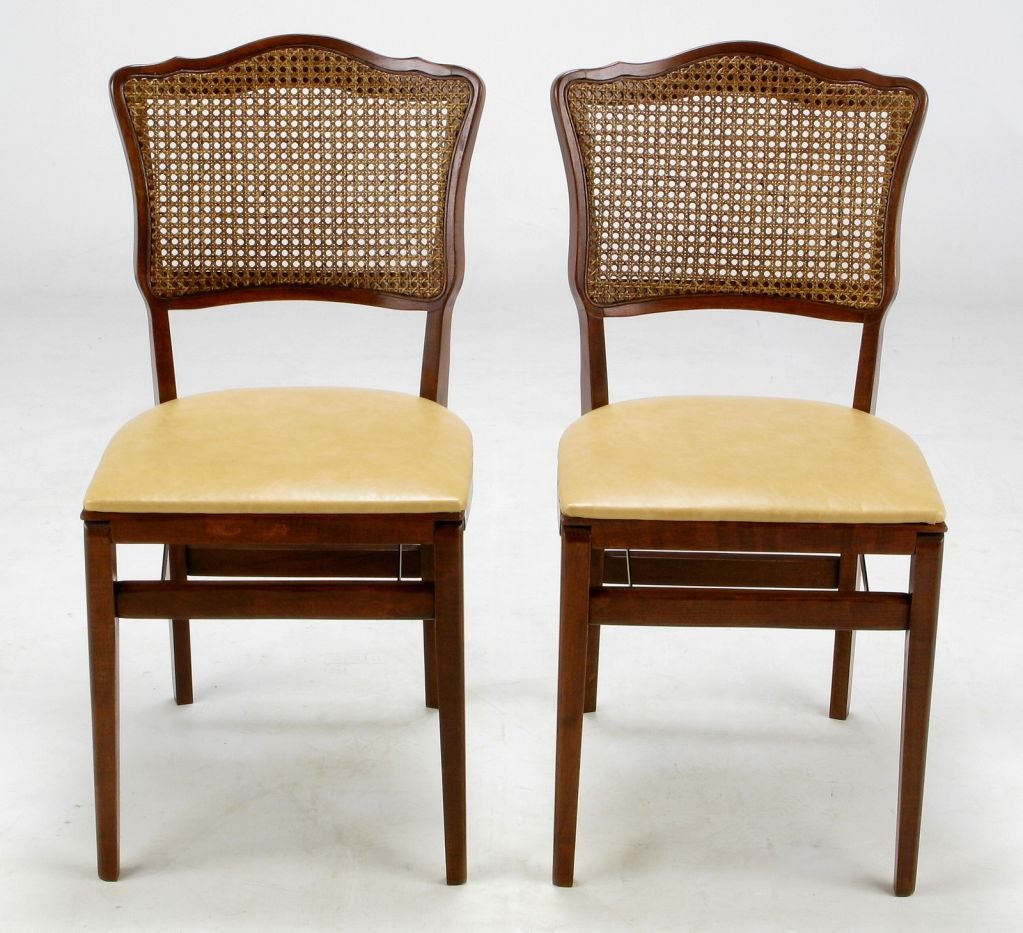 Unusual and rare set of Regency style folding dining chairs in mahogany and cane, with  dark ivory leather seats and scalloped backs. Extremely well constructed.  Just the right thing for occasional extra elegant seating.