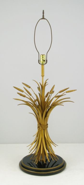 Wonderful and very large Italian sheaf of wheat tall lamp made of gilt tole metal. The base is a stepped black and gold lacquered carved wood disc with a retractable cord. Very unique and elegant table lamp. Sold sans shade.