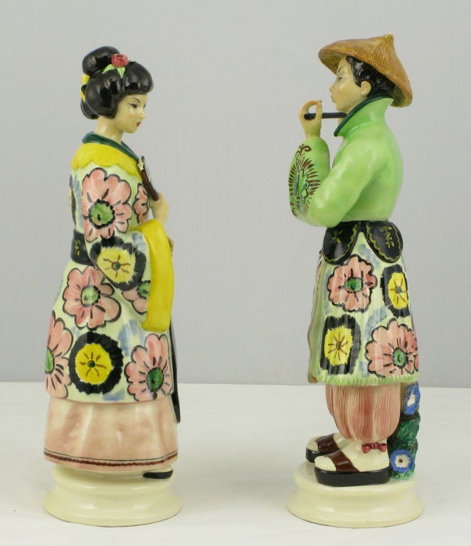 Traditionally dressed Italian pottery Asian man and woman figurines. Colorful hand painted glaze in pinks, greens, yellows, black and white.  Age is estimated, based upon maker's mark, and fragments of oilcloth to the undersides.  The Trevir
