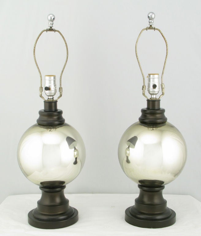 A brilliant pair of mercury glass globe table lamps. The center glass globe is supported by a lacquered resin sculptural base and topped by a lacquered resin cap. Sold sans shades.