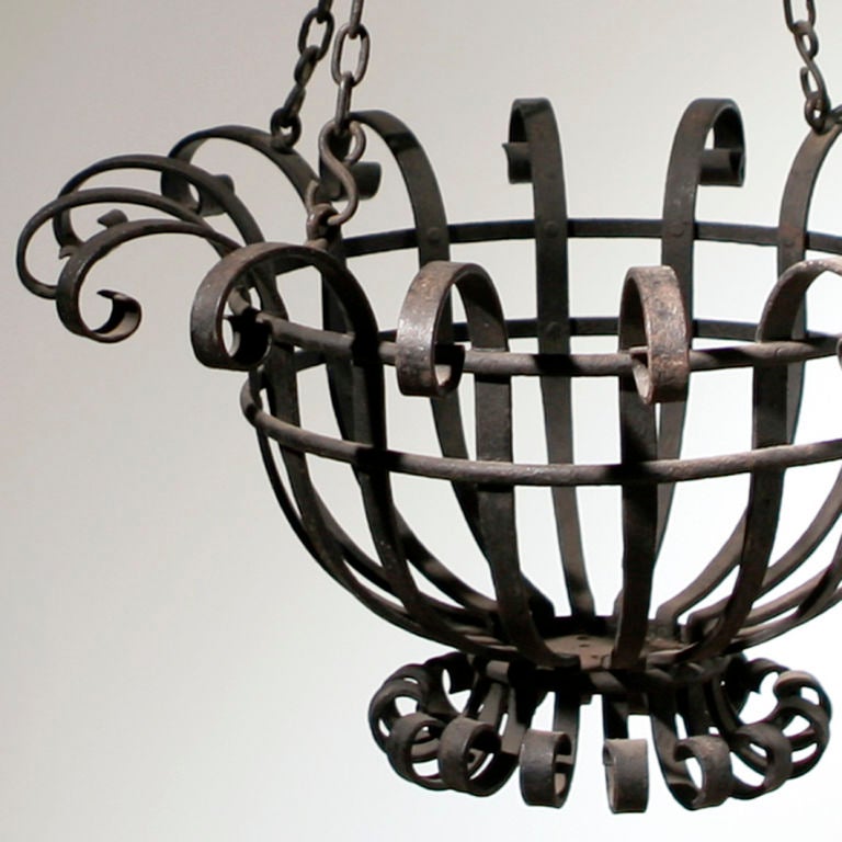 Extraordinary rare pair of large French wrought iron hanging baskets.  The open work baskets with scrolled edges are suspended from four iron chains and hooks.