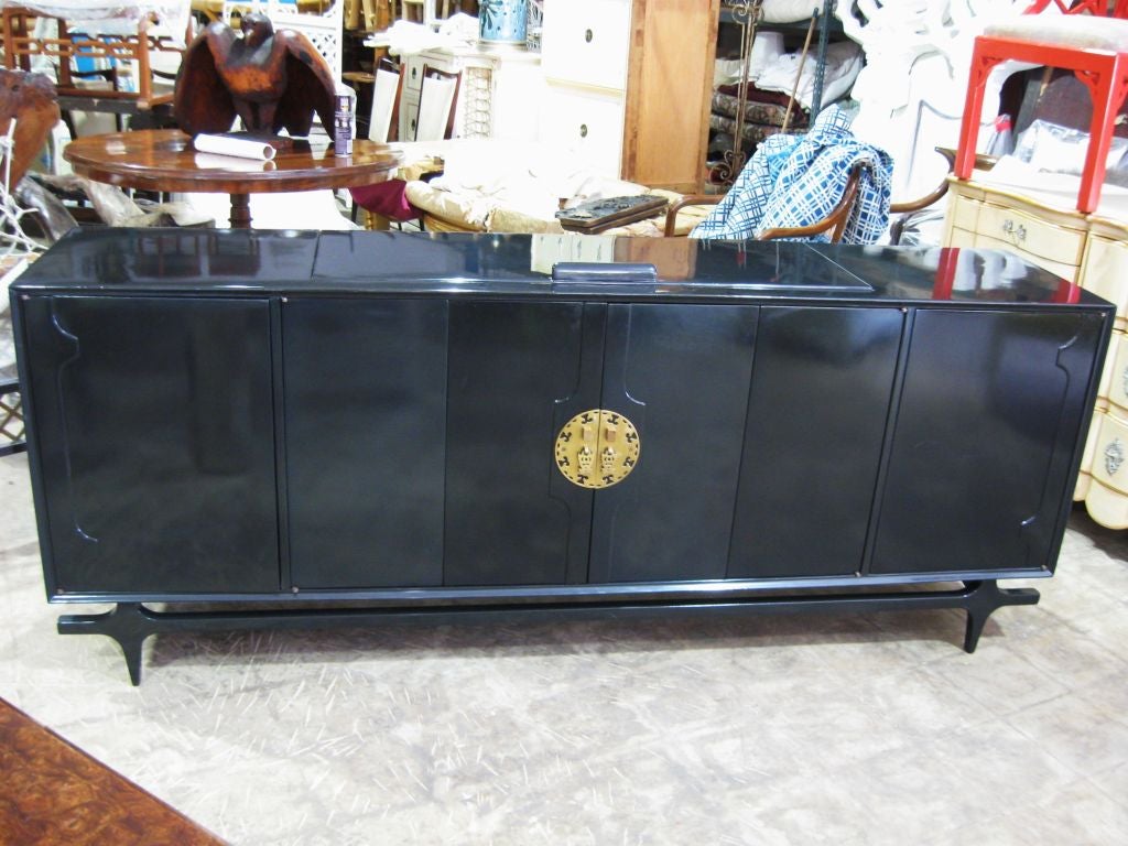 Lacquered neo Ming Chinoiserie style sideboard, with brass escussion and elegant tressel style base. Top flips open.<br />
Elegant tressel designer base.<br />
For additional sideboards, credenzas, cabinets, chests, dressers, servers, bureaus,