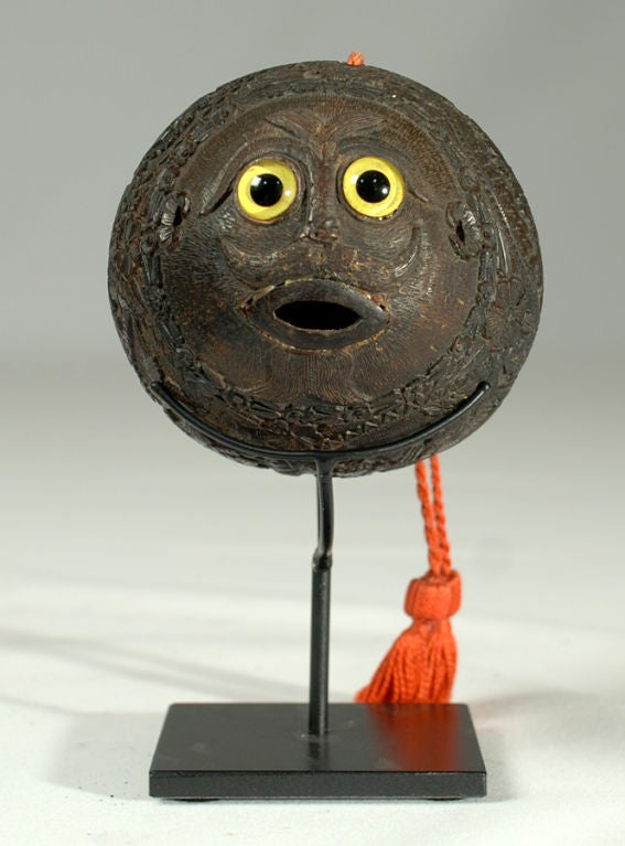 This exceedingly fine and rare early 20th century Mexican coconut bank is carved over almost every inch in beautiful detail. A series of vignettes illustrate the following: a bullfight, a pair of putti with banderole, a coat of arms and a finely