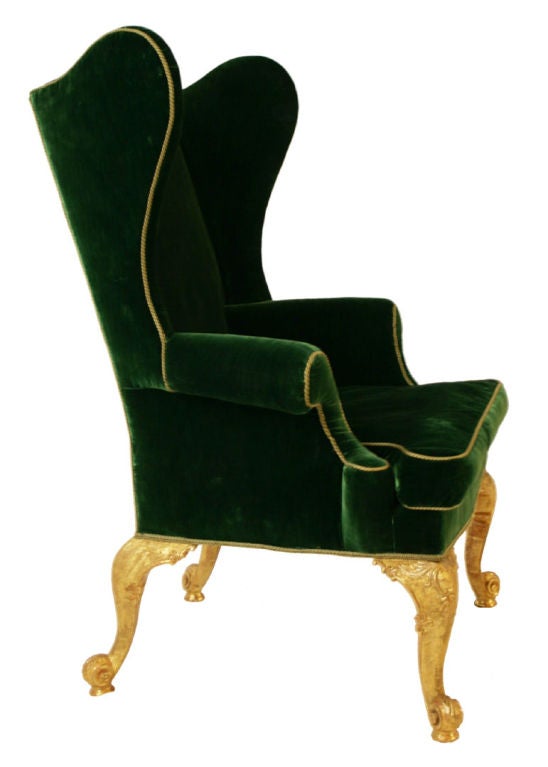 Rare George II upholstered wing chair with outscrolled arms raised on four giltwood cabriole legs with leaf and cabochon carved knees ending in scroll carved feet.<br />
<br />
Gilding refreshed on original preparation