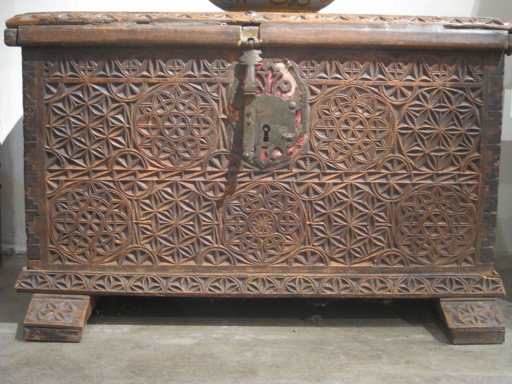 The rectangular top opening to two interior compartments, the top, front and sides carved with bold geometric motifs including the eight-pointed star, iron lock over red velvet, raised on carved feet