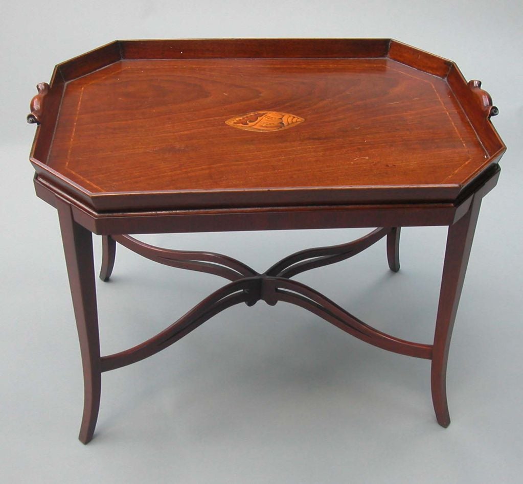 A George III mahogany tray on later custom stand. The 18th Century tray has carved and curled handles with laminated gallery and an octagonal form. The central inlaid shell is original. English, circa 1780-1800. (Tray only) and the base is later.
